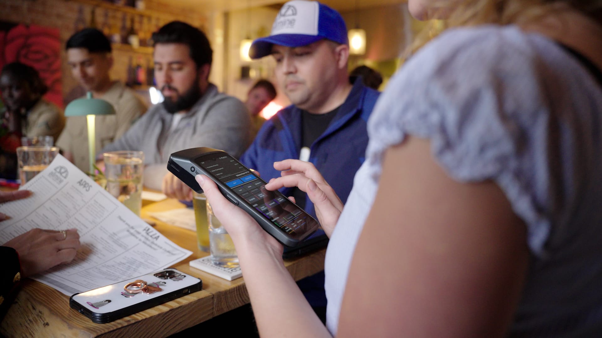 A server placing an order on a handheld at a hightop.