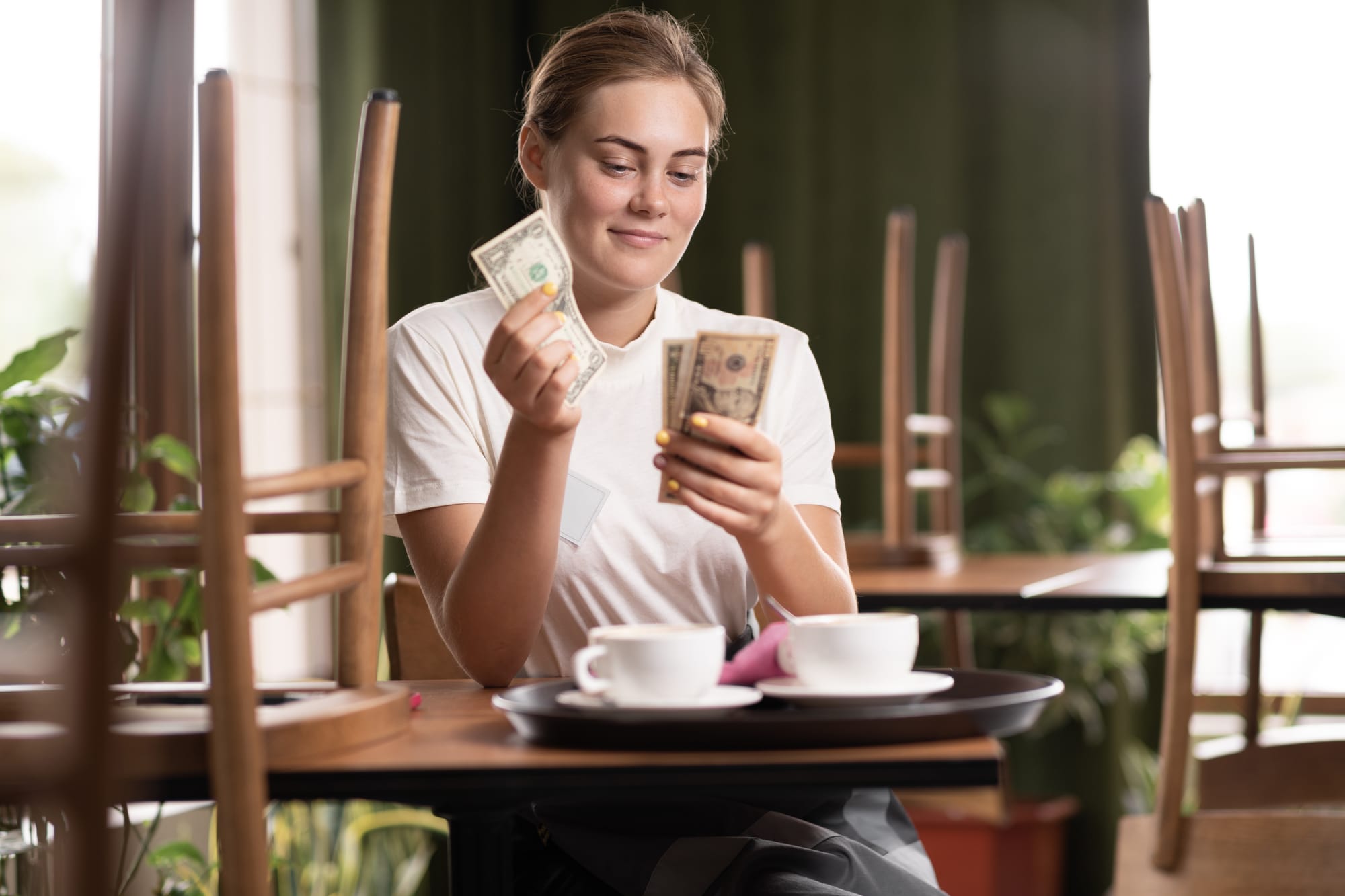 Server at a table counting tips from a check.