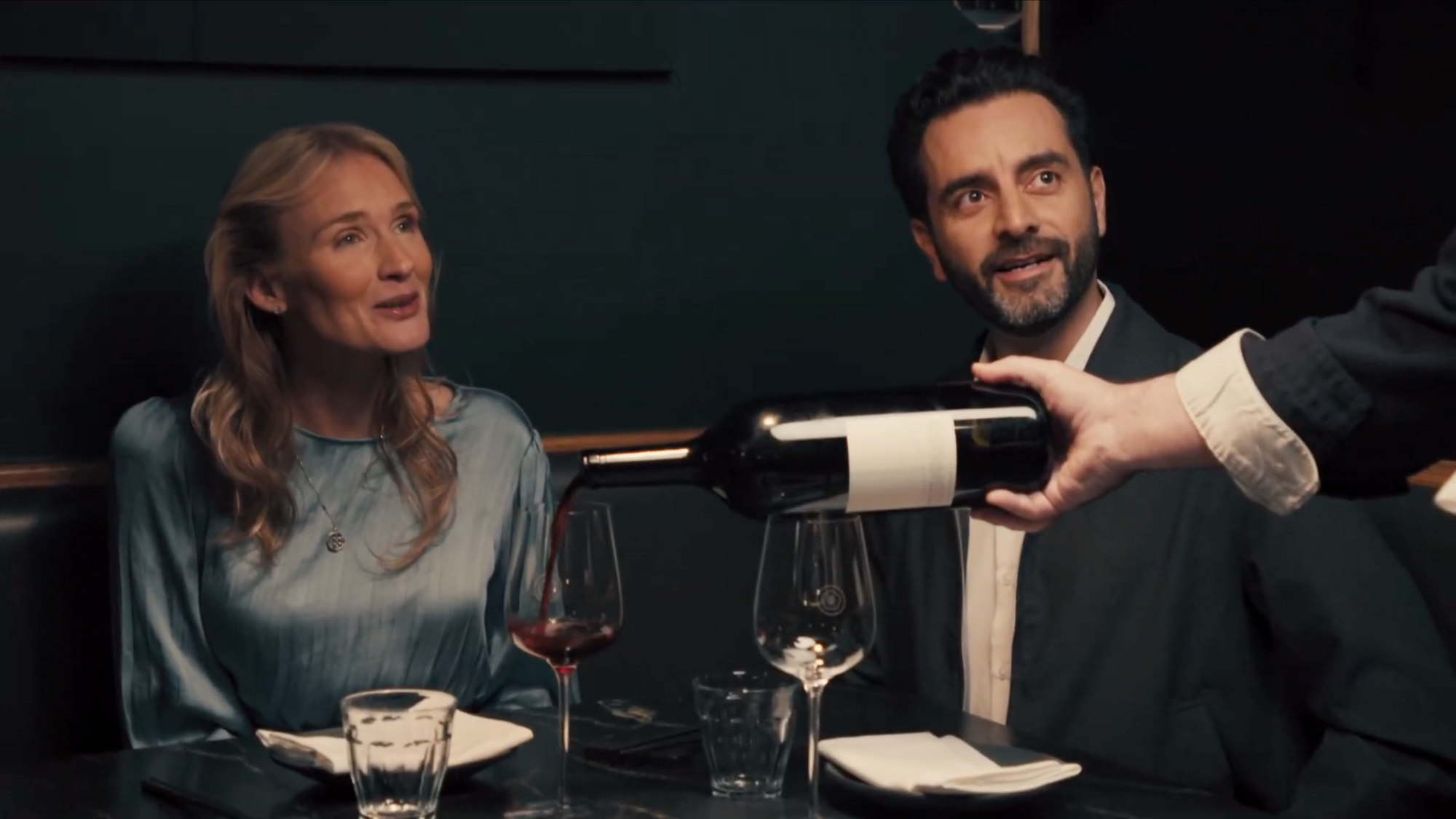 Guests at a table with while wine is being poured in glasses.