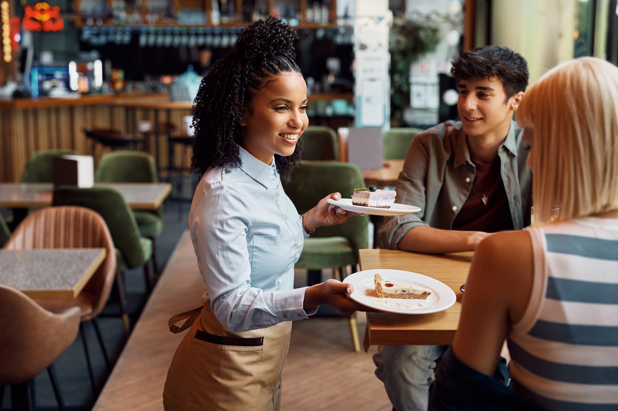 Server presenting desserts to a table at a restaurant.