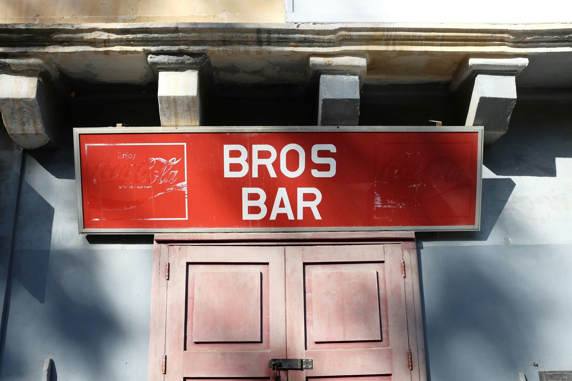 A red bar sign hangs above a door.
