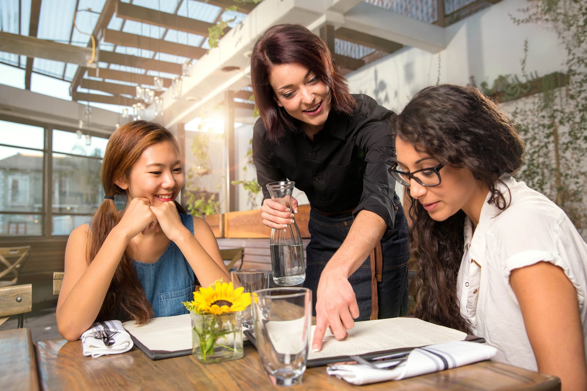 server showing menu to guests dining on restaurant patio