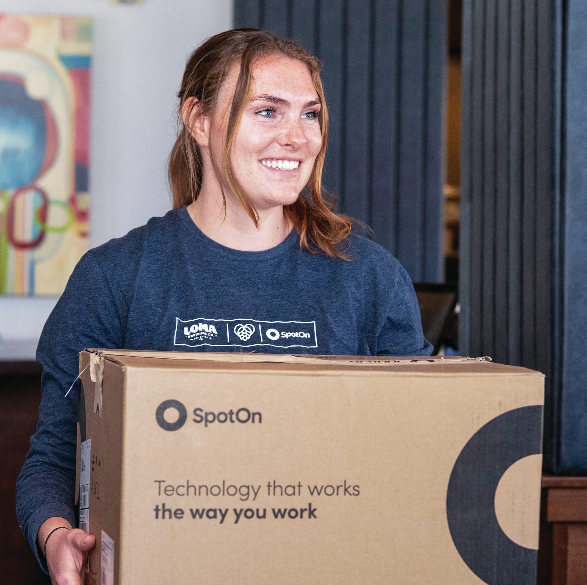 A SpotOn team member carries a SpotOn hardware delivery box inside a restaurant.