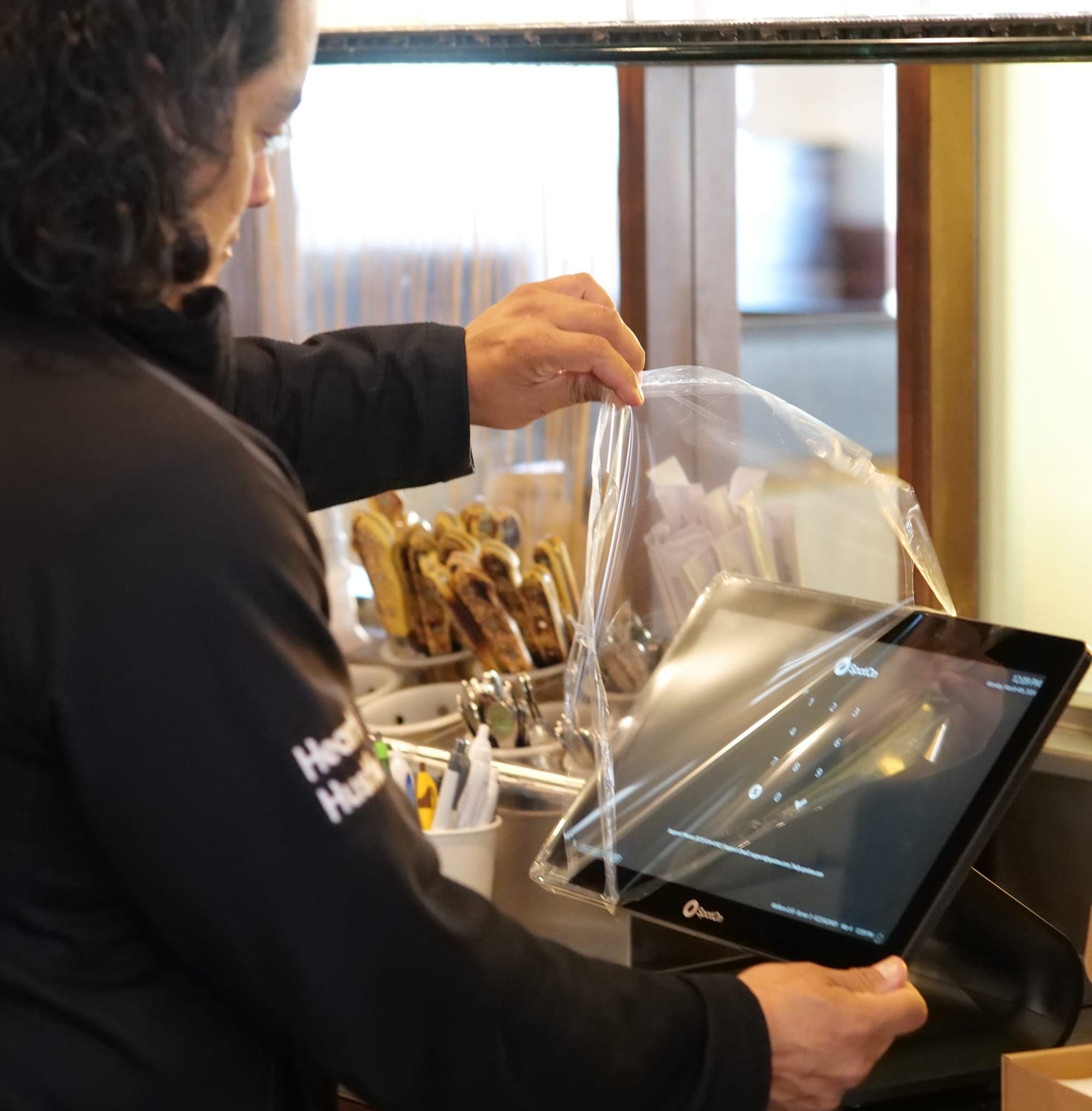 A SpotOn installer unwraps and sets up a SpotOn POS terminal at a restaurant counter.