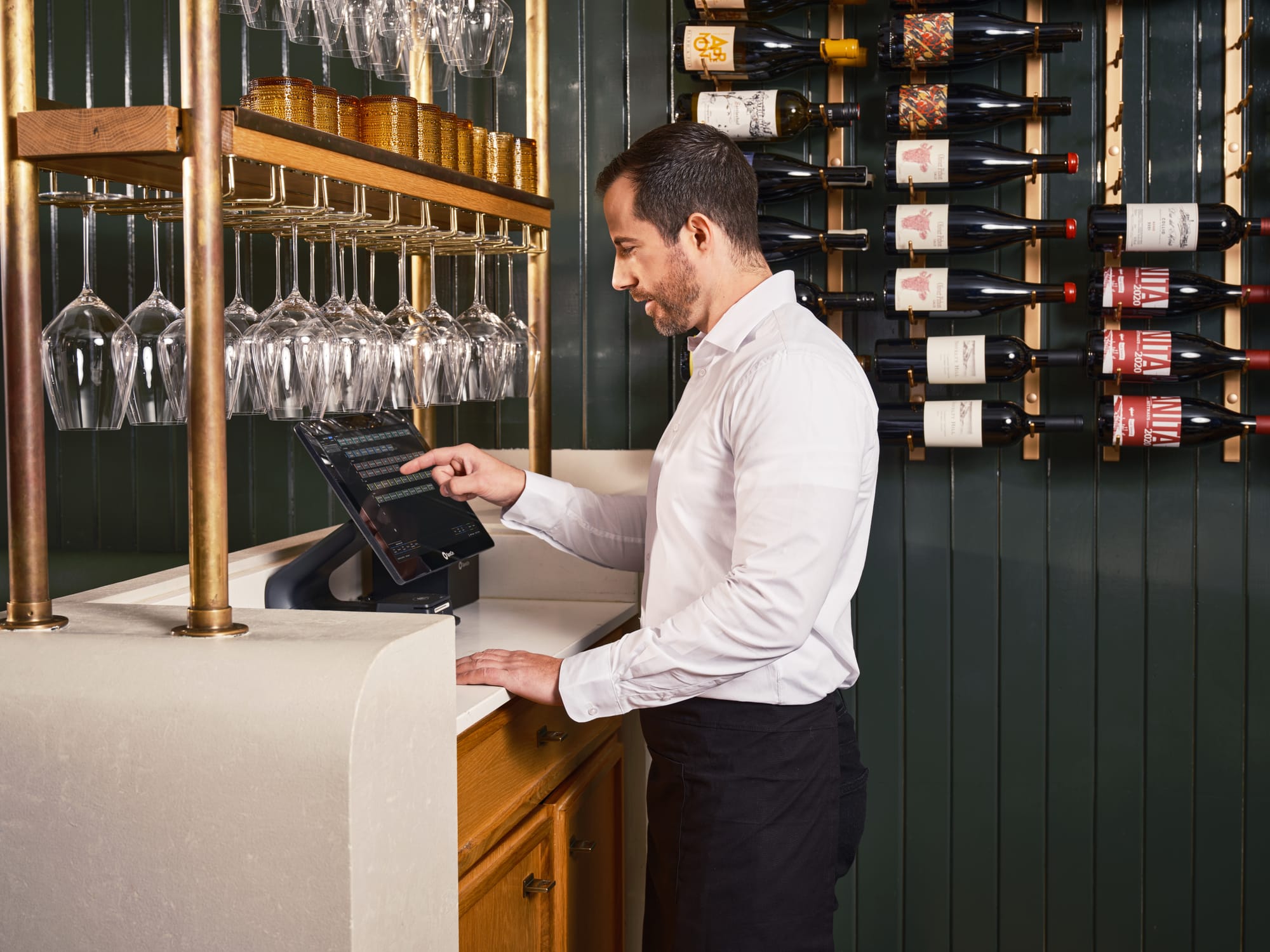 A server uses a SpotOn POS station to take an order in a fine dining restaurant.