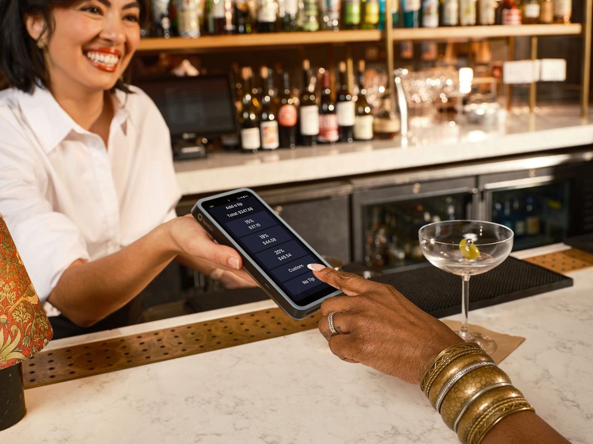 A bartender uses a SpotOn handheld POS device to speed up checkout at a restaurant