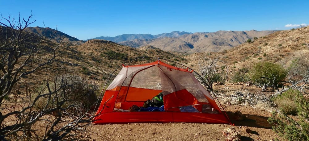 a backpacker's tent in the wilderness where they are communicating with satellite communicators