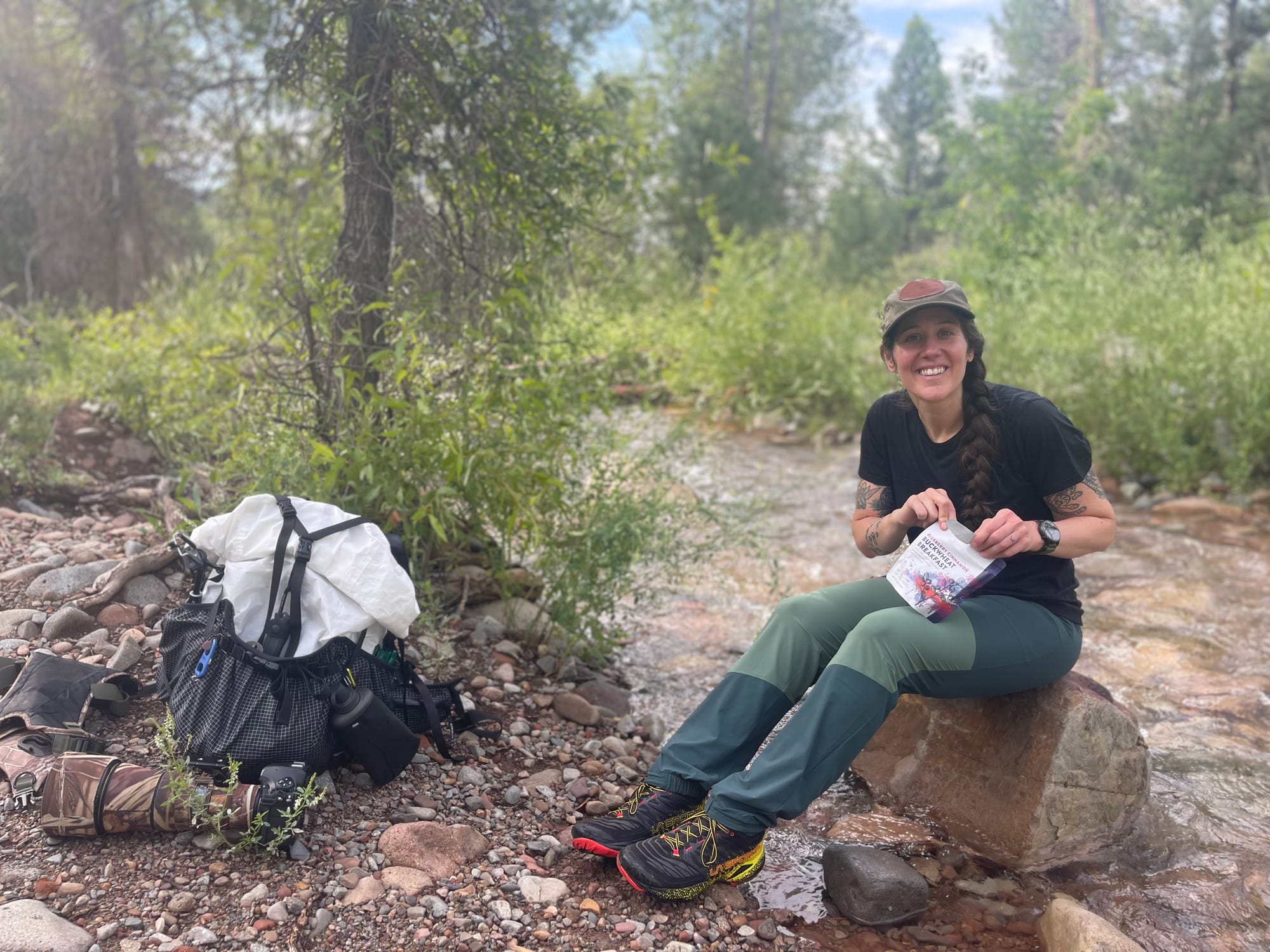 a hiker stops to have lunch along a mountain creek with a hyperlite mountain gear backpack next to her in 2026