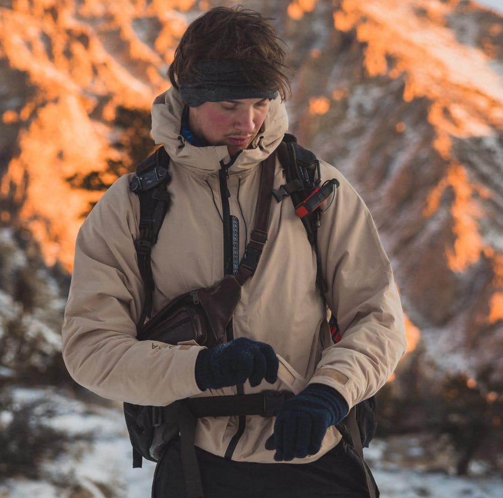a man wears the apu pakafill parka from paka in the snowy mountains