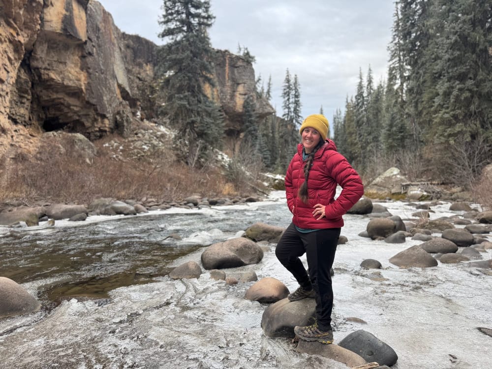 a hiker wears the katabatic gear tincup down jacket on a cold weather adventure along a creek