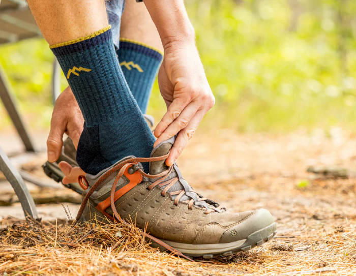 a hiker puts on his darn tough socks and hiking boots before setting off on trail. he wear micro crew hiking socks.