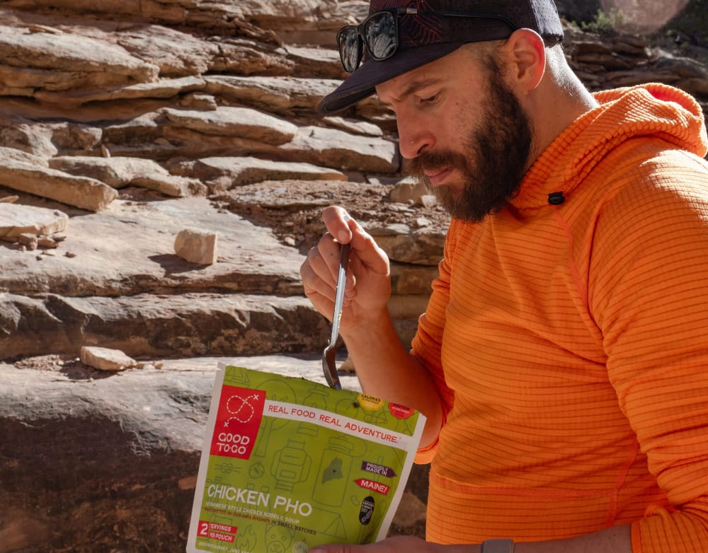 a man eats a good to-go dehydrated meal on a backpacking trip in the southwest