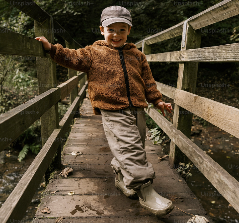 a little kid looking super excited about hiking over a wooden bridge