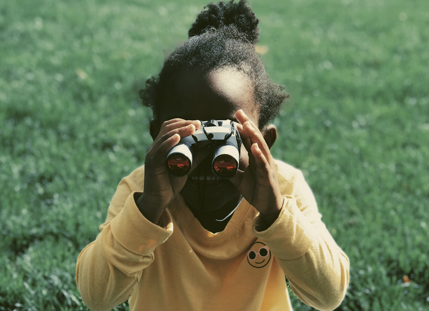a child on a hike looking through binoculars as a way to play and be curious