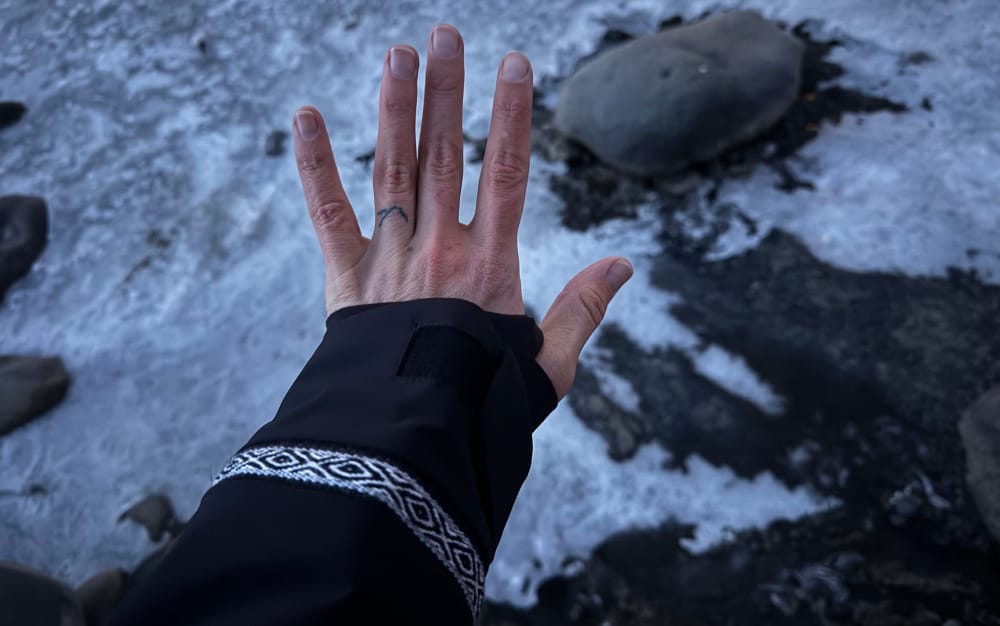 a hiker showing off details of the apu pakafill parka from paka like the interior cuff and woven design
