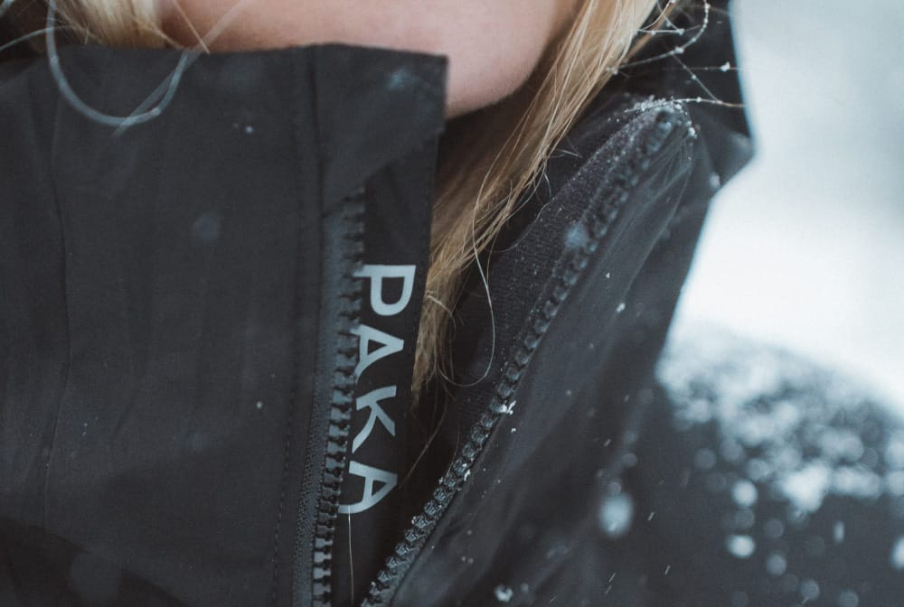pakafill jacket from paka being worn by a woman hiking on a snowy day. this is a close up with the paka logo