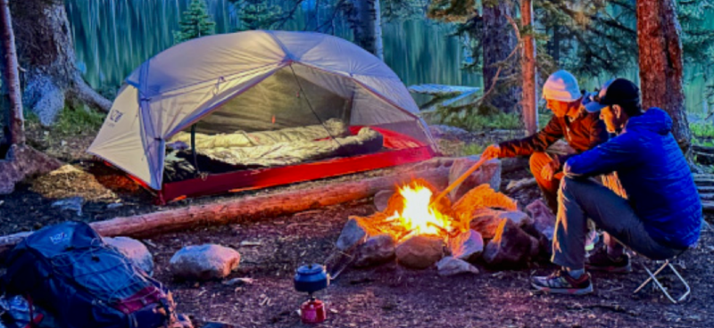 two backpackers using near zero gear in a woods campsite they saved big during the 2025 spring sale