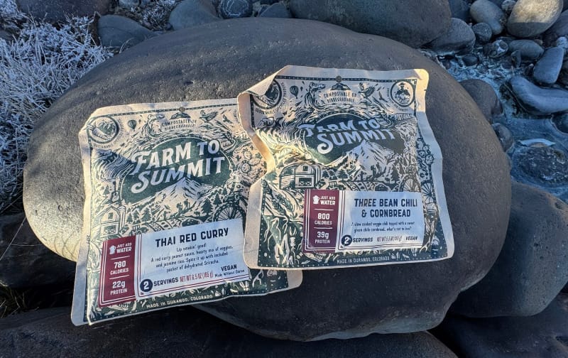 two farm to summit dehydrated backpacking meals sitting on river rocks in the southwest rockies on a trip