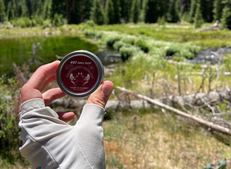 A backpacker holding farm to summit dehydrated sriracha in the mountains