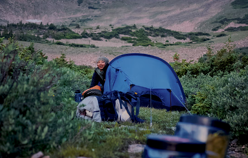a woman adventurer in a tent in the mountains with Fjällräven womens clothing and gear