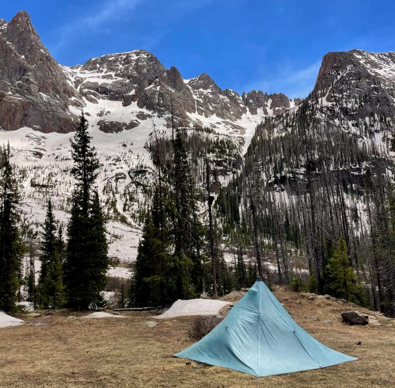 UltaMid 4 Ultralight Pyramid Tent By Hyperlite Mountain Gear pitched in a basin surrounded by snowy mountains.