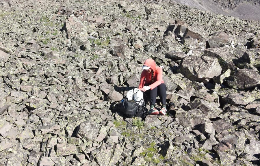 A woman hiking across a rocky talus field while wearing the Hyperlite Mountain Gear Southwest 70 backpack, highlighting its ultralight and durable design for challenging backcountry travel.