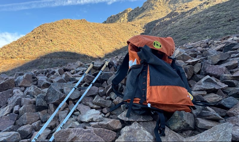 A hiker using the Six Moon Designs Wy’east Daypack on a scenic trail, highlighting its ultralight and functional design for day hikes.