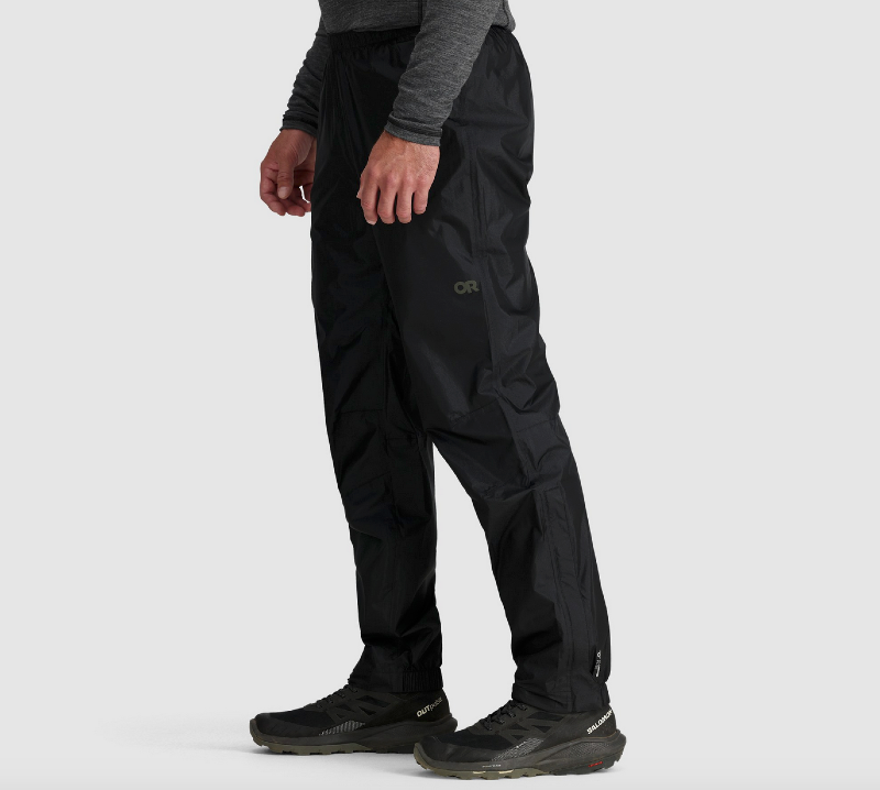 Person wearing Outdoor Research Helium rain pants while hiking, showing side profile with Salomon hiking shoes.