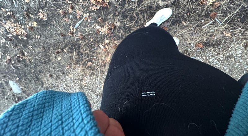  Photo looking down at black Branwyn leggings and white shoes on a forest trail, with a teal fleece visible in the corner of the frame.