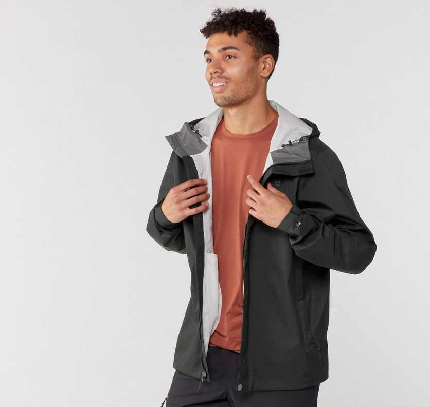 Man smiling and adjusting his REI Co-op Rainier rain jacket in black with light gray interior.