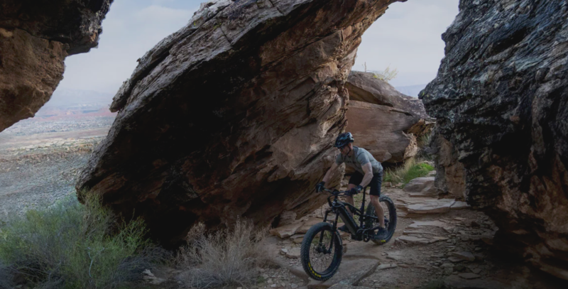 Rider tackles rocky desert terrain on a full-suspension Bakcou eBike beneath towering sandstone formations