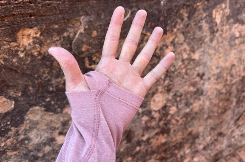  Close-up of thumb loop sleeve on the PAKA SOL Hoodie sun shirt against red rock canyon background.