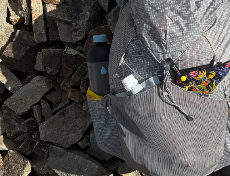  Mazama M!GO water bottle stored in the side pocket of an ultralight backpack on rocky ground.