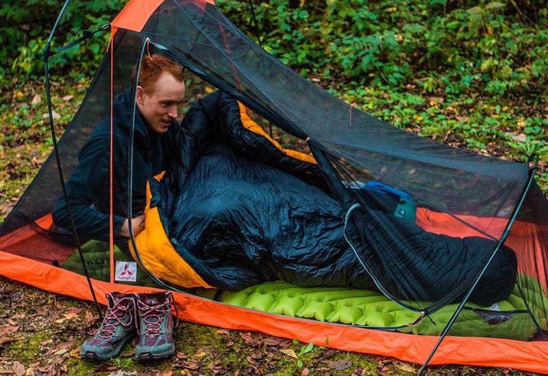  Camper inside a lightweight tent using Enlightened Equipment Conundrum Quilt with yellow interior