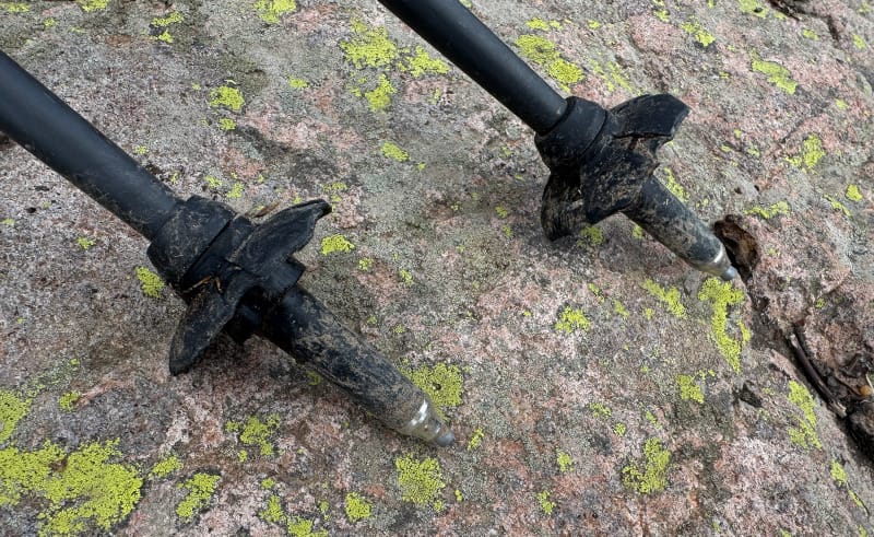Close-up of carbide trekking pole tips from Gossamer Gear resting on granite rock.