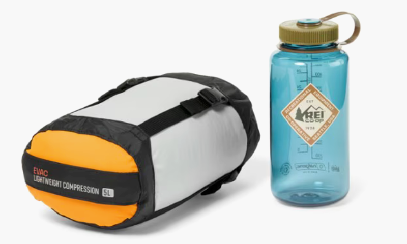 Compression sack next to a blue REI Co-op Nalgene water bottle for backpacking gear comparison.
