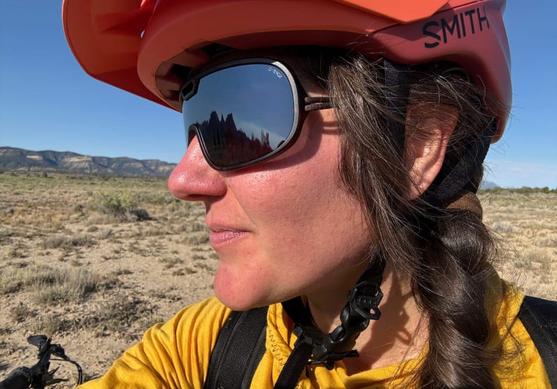  Person wearing Ombraz Refugio sunglasses with a bike helmet in the desert landscape.