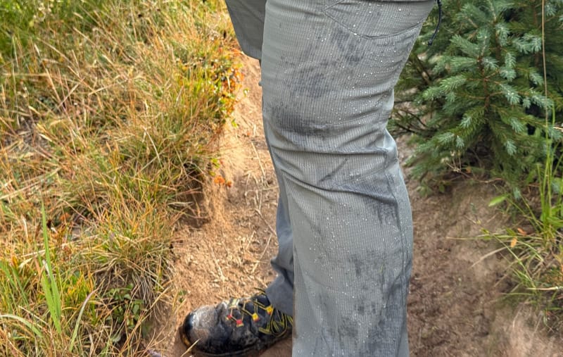 Close-up of KUIU Tiburon Pants showing water-resistant fabric with droplets beading on the material during a hike.