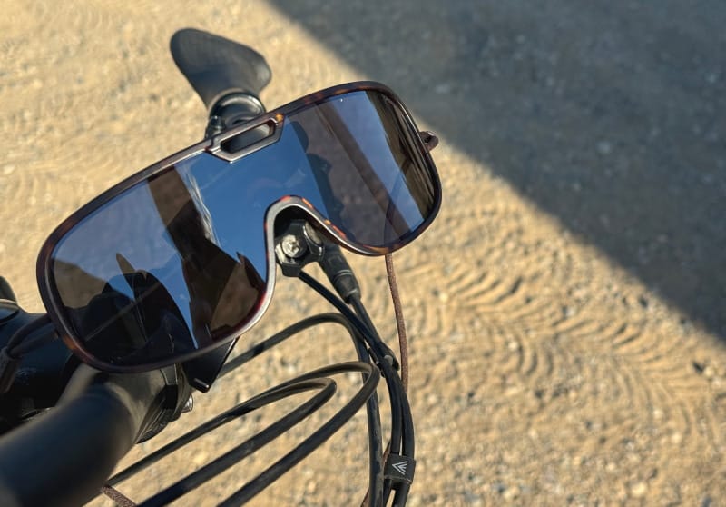  Ombraz Refugio sunglasses resting on a bike handlebar in the desert sun.