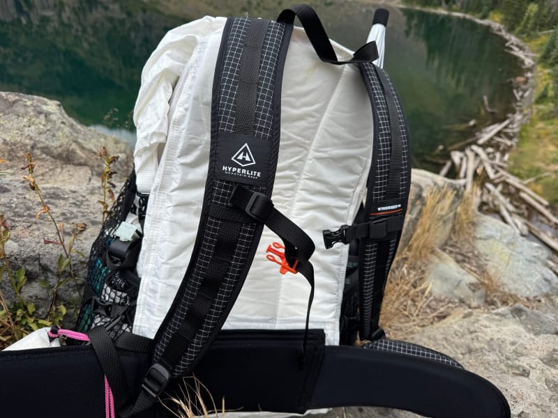 Side view of the Hyperlite Windrider 70 Backpack resting on rocks near an alpine lake, highlighting Dyneema fabric and strap system.