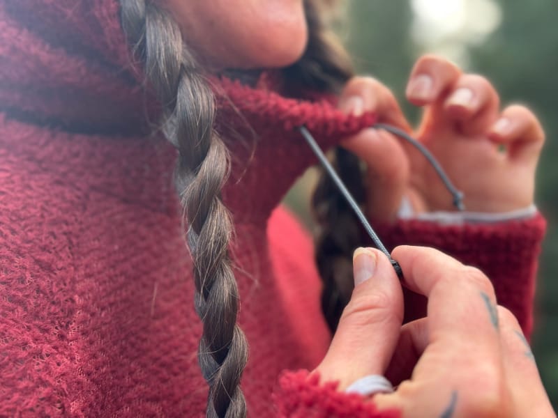 Close-up of a hiker tightening the drawcord on the FarPointe Alpha Cruiser hood, showing the textured Polartec Alpha fleece fabric.
