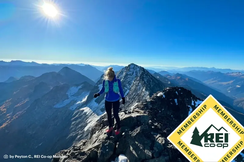 A hiker on a mountain ridge with rei membership logo in 2026