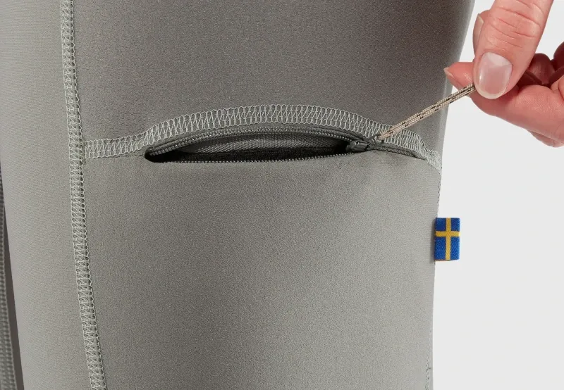 Close-up of a zippered pocket on Fjallraven Abisko Tights, showing Swedish flag logo and smooth stretch fabric.