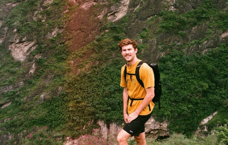 Backpacker wearing a lightweight pack while hiking through a steep green canyon landscape
