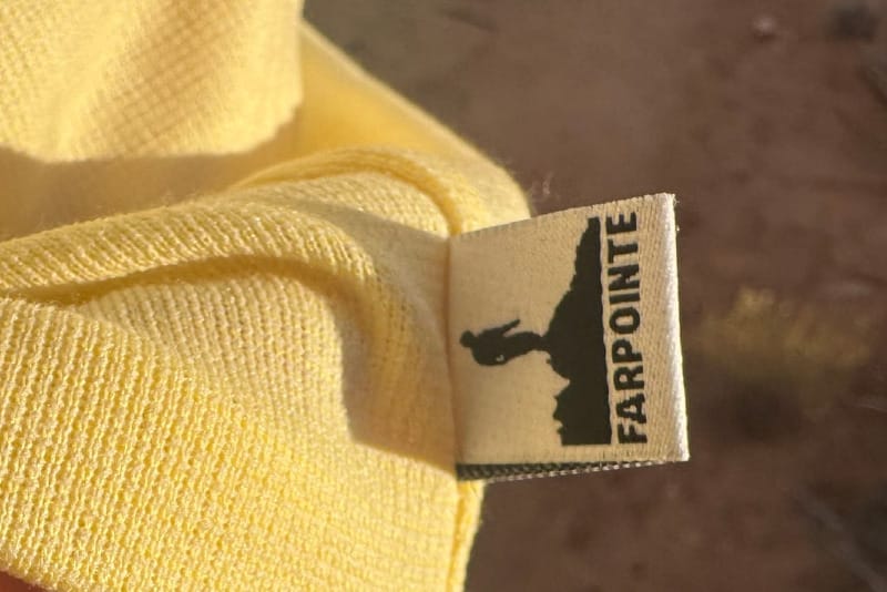 Close-up of the FarPointe Sun Cruiser fabric and logo tag, showing the lightweight yellow power wool in warm desert light.