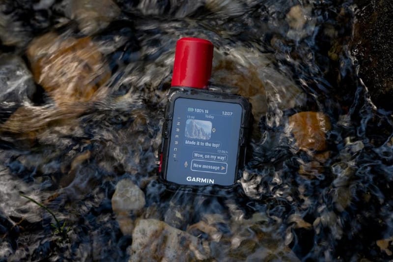 Garmin inReach Mini 3 Plus satellite communicator submerged in a flowing stream, demonstrating waterproof durability for hiking, backpacking, and backcountry travel.