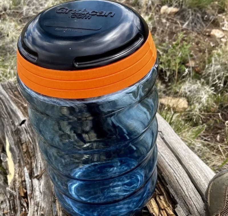 Close-up of the Grubcan Wave bear canister showing wave-shaped design and tool-free lid for backpacking food storage