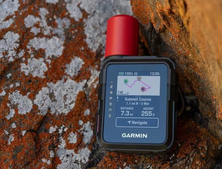 Garmin inReach Mini 3 Plus showing a mapped summit course and distance information while resting on a rock in alpine terrain.