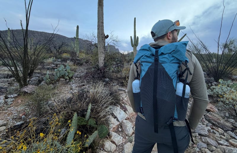 a hiker wearing a backpack in the desert with ingneous gear nobo bottles.