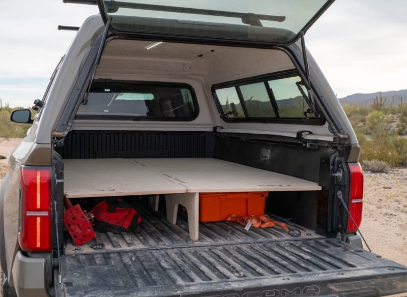 Rear view of Toyota Tacoma truck bed with BamBeds full sleeping platform installed for truck camping in desert landscape.